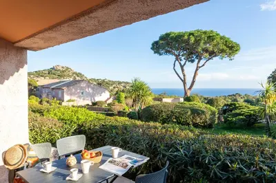 a table and chairs on a patio with a view of the ocean at Costa Marina in Porto-Vecchio
