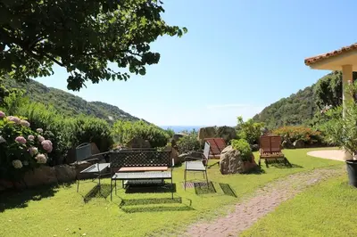 a group of chairs and a table in the grass at CORSACASA Villa in Palombaggia sea view in Porto-Vecchio