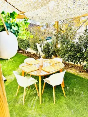 a wooden table and chairs in a garden at T2 « Bohème » avec Spa… in Calenzana