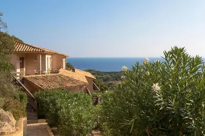 a house on a hill with the ocean in the background at Les Terrasses de Scalegiu in Porto-Vecchio