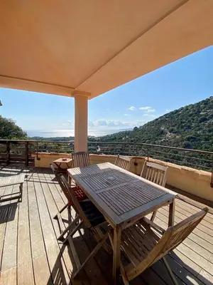 a table and chairs on a deck with a view at Les Terrasses de Scalegiu in Porto-Vecchio