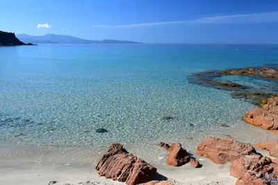 a beach with rocks in the water and the ocean at Appartement avec vue sur la montagne in Vico