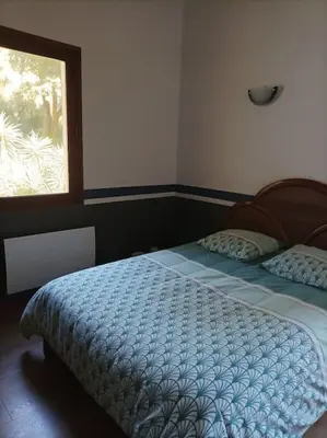 a bedroom with a bed with a blue comforter and a window at Appartement avec vue sur la montagne in Vico