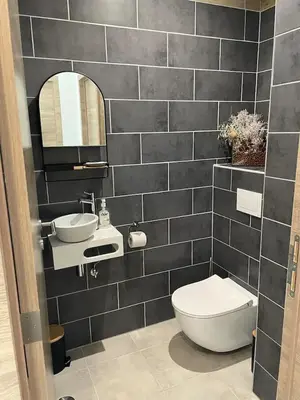 a black tiled bathroom with a toilet and a sink at Villa Casa Sognu di Orizonte in Figari