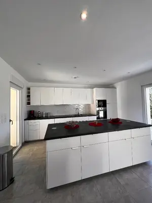 a kitchen with white cabinets and a black counter top at Villa Casa Sognu di Orizonte in Figari