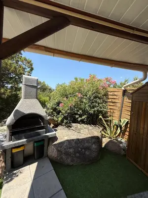 a patio with an outdoor grill in a garden at Studio de charme à 300 m de la Plage de Santa Giulia in Porto-Vecchio