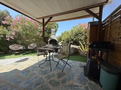 a patio with a table and chairs and a grill at Studio de charme à 300 m de la Plage de Santa Giulia in Porto-Vecchio