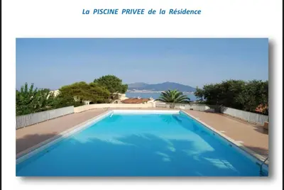 a large blue swimming pool with the ocean in the background at Appartement terrasse 1 chambre in Porticcio