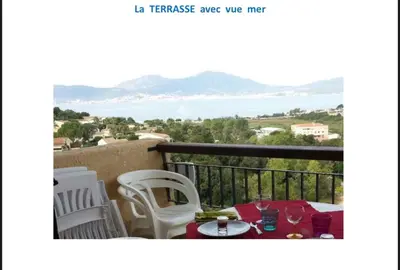 a balcony with a table and chairs with a view of the ocean at Appartement terrasse 1 chambre in Porticcio