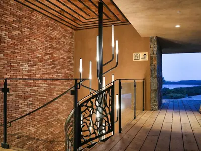 a staircase in a house with a brick wall and chandeliers at Les Regalia Hôtel & Spa in Sainte-Lucie de Porto-Vecchio