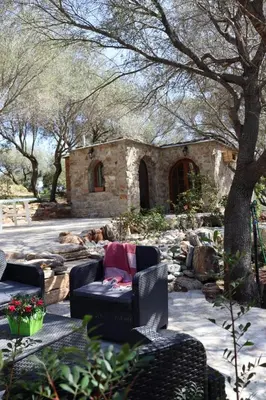 a garden with two chairs and a stone building at BERGERIE LA NEPITA in Saint-Florent