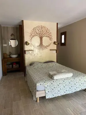 a bedroom with a bed with a tree mural on the wall at BERGERIE LA NEPITA in Saint-Florent