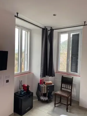 a living room with a chair and two windows at LE RELAIS DES COLS in Cozzano
