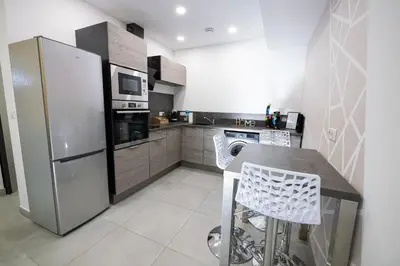 a kitchen with a refrigerator and a table and chairs at N10 Maison T2 climatisé avec jacuzzi privé in Ajaccio