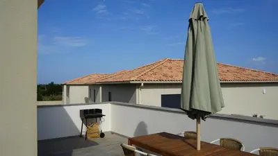 a green umbrella sitting on a table on a balcony at Résidence Petra Paolina in Folelli