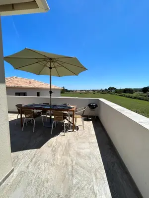 a patio with a table and an umbrella at Résidence Petra Paolina in Folelli