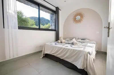 a bedroom with a bed and a large window at N1 Maison T2 climatisé in Ajaccio