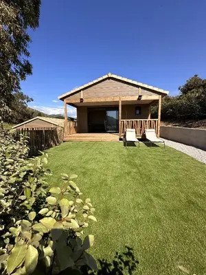 a house with a lawn and two chairs in front of it at Les collines de lava in Appietto