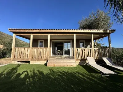 a house with a deck and two chairs on the grass at Les collines de lava in Appietto