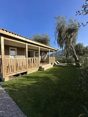 a house with a porch and a grass yard at Les collines de lava in Appietto