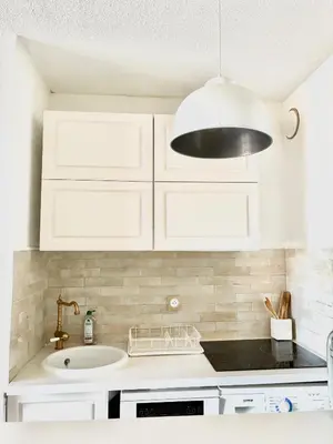 a kitchen with white cabinets and a sink at Le Cocon de Lilie in San-Nicolao