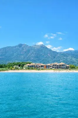 a resort on a beach with mountains in the background at Le Cocon de Lilie in San-Nicolao