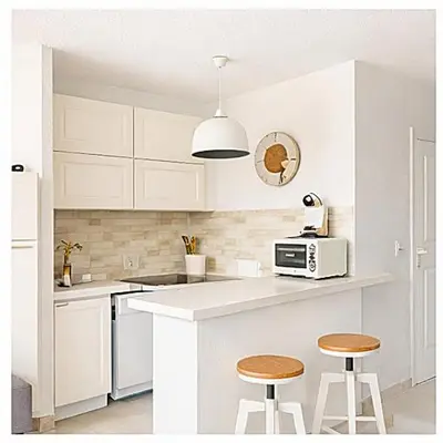 a white kitchen with a microwave and two bar stools at Le Cocon de Lilie in San-Nicolao