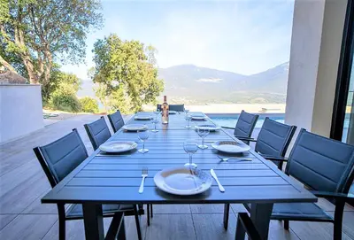 a long blue table with plates and wine glasses at Villa Elora vue mer et piscine in Viggianello