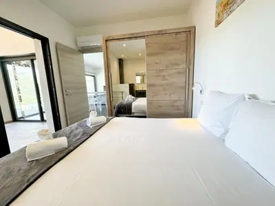 a bedroom with a large white bed with a sliding door at Villa Elora vue mer et piscine in Viggianello