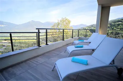 a balcony with white chairs and a view of the mountains at Villa Elora vue mer et piscine in Viggianello