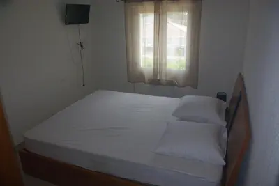 a bedroom with a bed with white sheets and a window at Résidence A NUCIOLA Les pieds dans l'eau Cervione Hte CORSE in Cervione