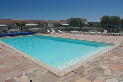 a large swimming pool with blue water in a patio at Résidence A NUCIOLA Les pieds dans l'eau Cervione Hte CORSE in Cervione