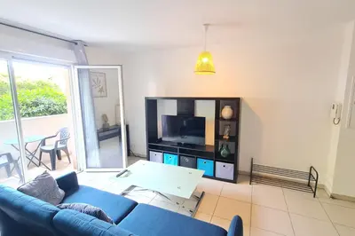 a living room with a blue couch and a tv at Charming 45m in Sarrola carcopino in Sarrola-Carcopino