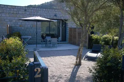 a patio with an umbrella and a table and chairs at N2 Maison T2 climatisé in Ajaccio