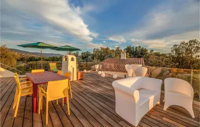 a wooden deck with chairs and tables and an umbrella at Lovely Home In Porticcio in Porticcio