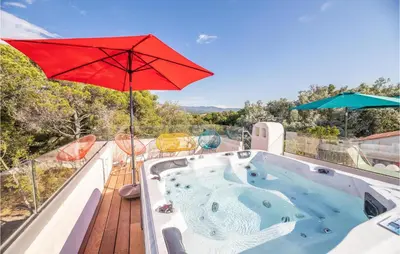 a hot tub on a deck with a red umbrella at Lovely Home In Porticcio in Porticcio