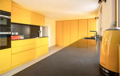 a kitchen with yellow cabinets and a black counter top at Lovely Home In Porticcio in Porticcio