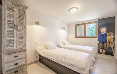 a bedroom with two beds and a painting on the wall at Lovely Home In Porticcio in Porticcio