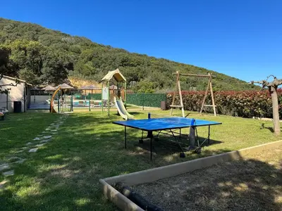 a ping pong table in a yard with a playground at Résidence de tourisme Les Hauts de l'Avena in Sartène