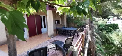 a patio with a table and chairs and trees at Résidence de tourisme Les Hauts de l'Avena in Sartène
