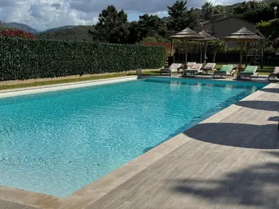 a swimming pool with chairs and a gazebo at Résidence de tourisme Les Hauts de l'Avena in Sartène