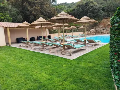 a group of lounge chairs and umbrellas next to a pool at Résidence de tourisme Les Hauts de l'Avena in Sartène