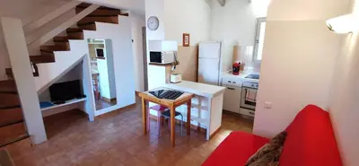 a living room with a table and a kitchen at Résidence de tourisme Les Hauts de l'Avena in Sartène