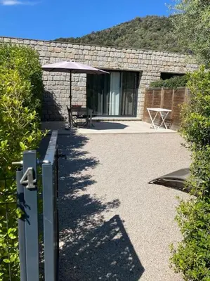 a stone house with a table and an umbrella at N4 Maison T2 climatisé in Ajaccio