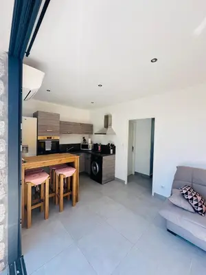 a kitchen and living room with a table and a couch at N4 Maison T2 climatisé in Ajaccio