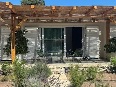 a patio with two chairs and a pergola at CasaCanetto villa, suites et piscine chauffée in Bonifacio