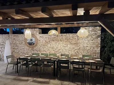 a dining room with a table and chairs and a brick wall at CasaCanetto villa, suites et piscine chauffée in Bonifacio