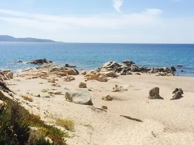 a sandy beach with rocks and the ocean at RAS L'BOL in Olmeto
