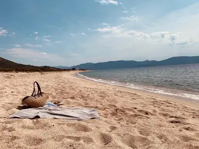 a basket sitting on a beach next to the water at RAS L'BOL in Olmeto