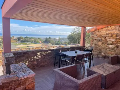 a patio with a table and chairs and a stone wall at La Bergerie Furiani avec piscine privée Residence Digoune in Furiani